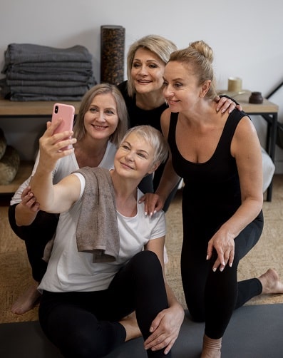 Mulheres de diferentes idades, em ambiente de atividade física, vestindo roupas apropriadas, posam para selfie.
O envelhecimento saudável envolve cuidados não apenas estéticos, mas também físicos.